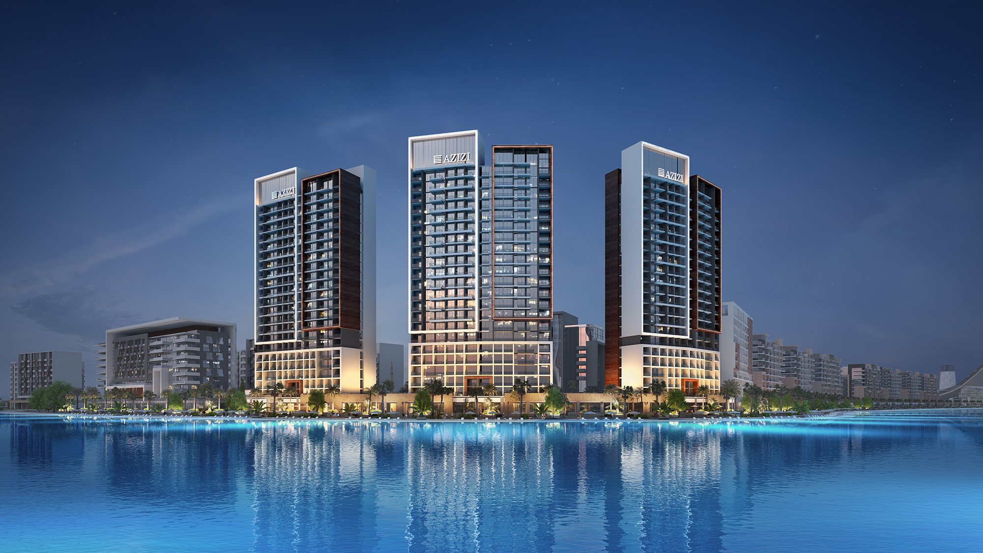 Azizi Riviera towers illuminated at night reflecting on the lagoon waters
